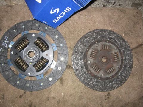 1989 Ford Bronco - A new Sachs clutch disc is shown next to a worn-out clutch disc, with the Sachs packaging in the background.