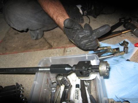 1989 Ford Bronco - A gloved hand gestures with the middle finger over a driveshaft part and various tools laid out on a blue shop towel.