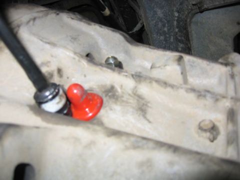 1989 Ford Bronco - A close-up view of a vehicle's clutch slave cylinder line, a red protective cap.