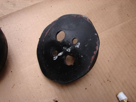 1973 Ford Ranchero - A black-painted metal pulley or hub with worn paint revealing red/orange primer, showing several drilled holes and a threaded stud in the c…