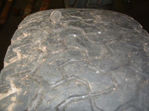 1994 Jeep YJ - A quarter sits on the tread of a used tire, showing its wear pattern.