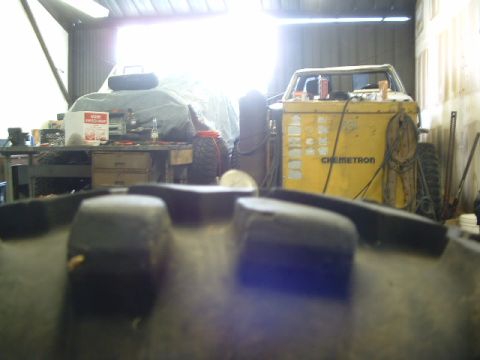 1994 Jeep YJ - A Jeep CJ-7 is seen inside a garage, partially covered, with a welding machine nearby.