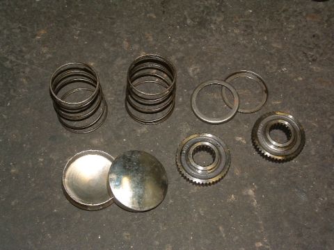 1994 Jeep YJ - Various transmission components, including gears, springs, and caps, are laid out on a textured dark surface.
