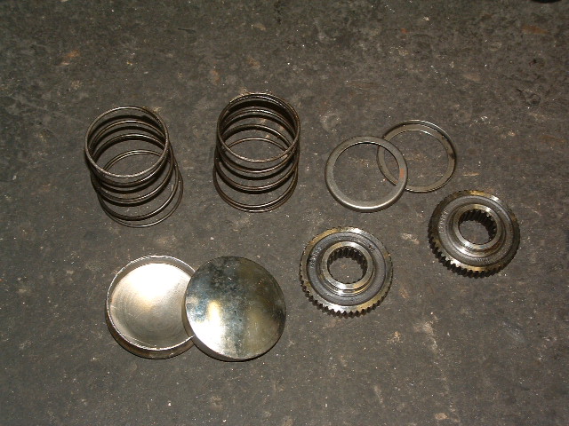 Transmission gears, springs, and caps on a dark surface
