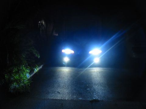 1995 Ford Thunderbird - Two vehicles approach on a dark, wet road, their headlights illuminating the scene.