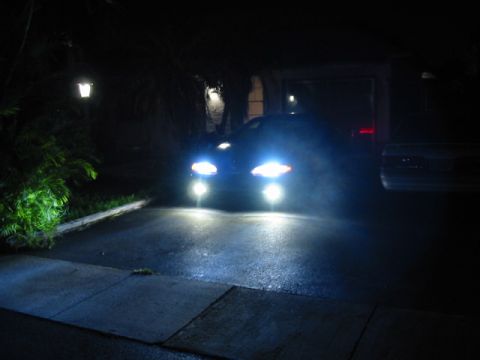 1995 Ford Thunderbird - A car's bright headlights illuminate a driveway at night, obscuring details of the vehicle itself.