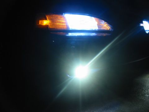 1995 Ford Thunderbird - Close-up of a car's front lighting system, including the headlight and fog light, illuminated in the dark.