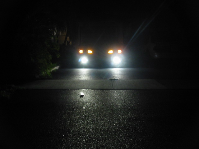 Vehicle front with bright headlights and amber turn signals at night