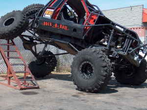1989 Ford Bronco - This heavily modified off-road vehicle, likely a custom build, is positioned on a ramp, its extreme suspension and large tires.