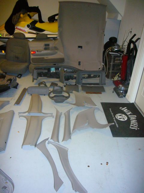 2000 Ford Crown Victoria - Various interior car parts are laid out on the floor, suggesting a disassembled vehicle.