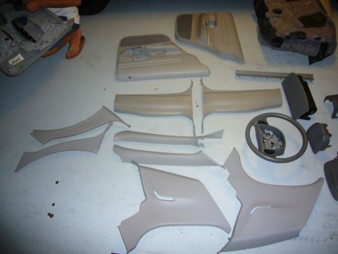 2000 Ford Crown Victoria - Interior trim pieces and steering wheel from a car are disassembled and laid out on the floor.