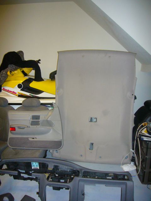 2000 Ford Crown Victoria - Disassembled car interior components are stored indoors alongside a personal watercraft.
