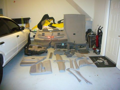 2000 Ford Crown Victoria - Interior parts from a 2000 Ford Crown Victoria are laid out on the floor next to the vehicle.