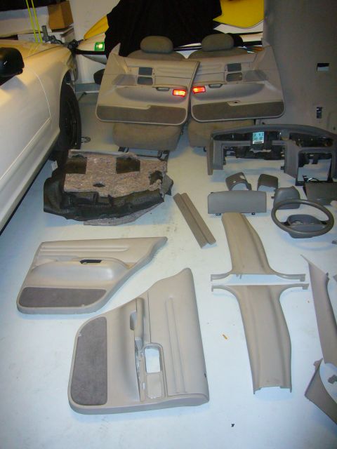 2000 Ford Crown Victoria - Interior components from a car are disassembled and spread out on the floor.