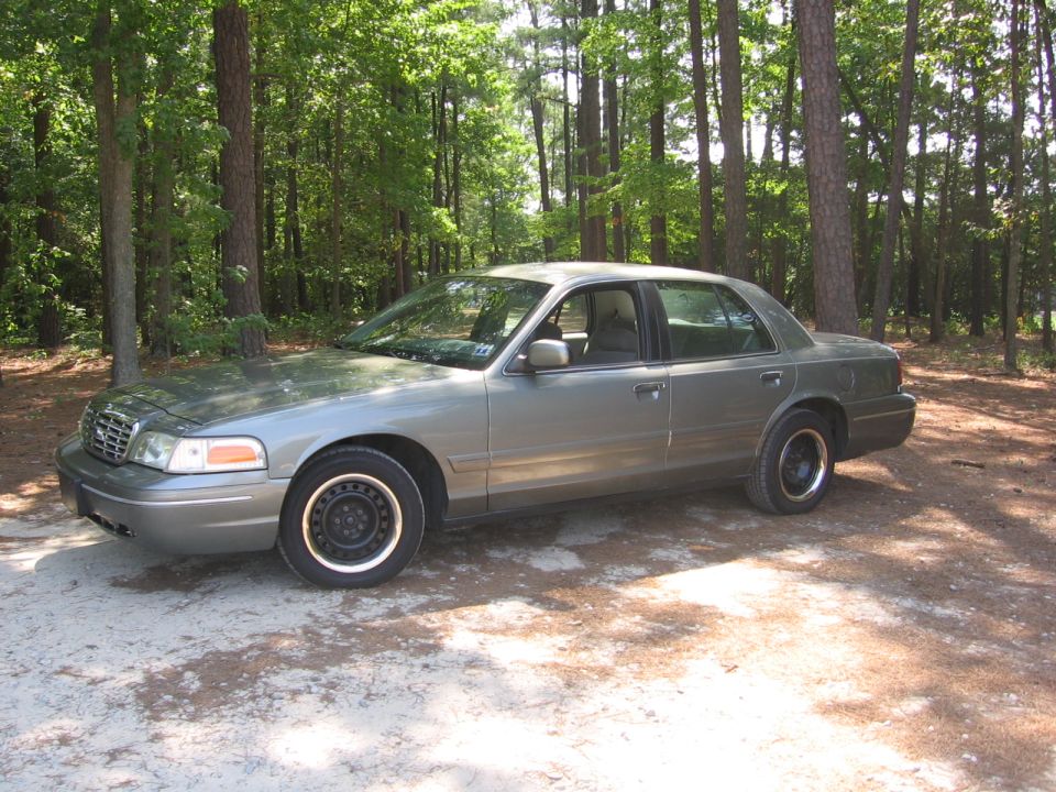 2000 Ford Crown Victoria parked on a dirt road in a wooded area