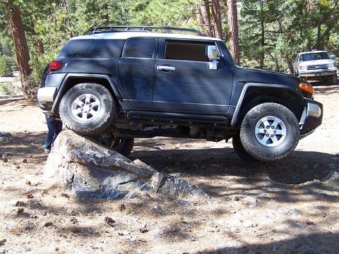 1991 Ford Bronco - A dark-colored SUV is seen driving on a dirt road, possibly off-road.