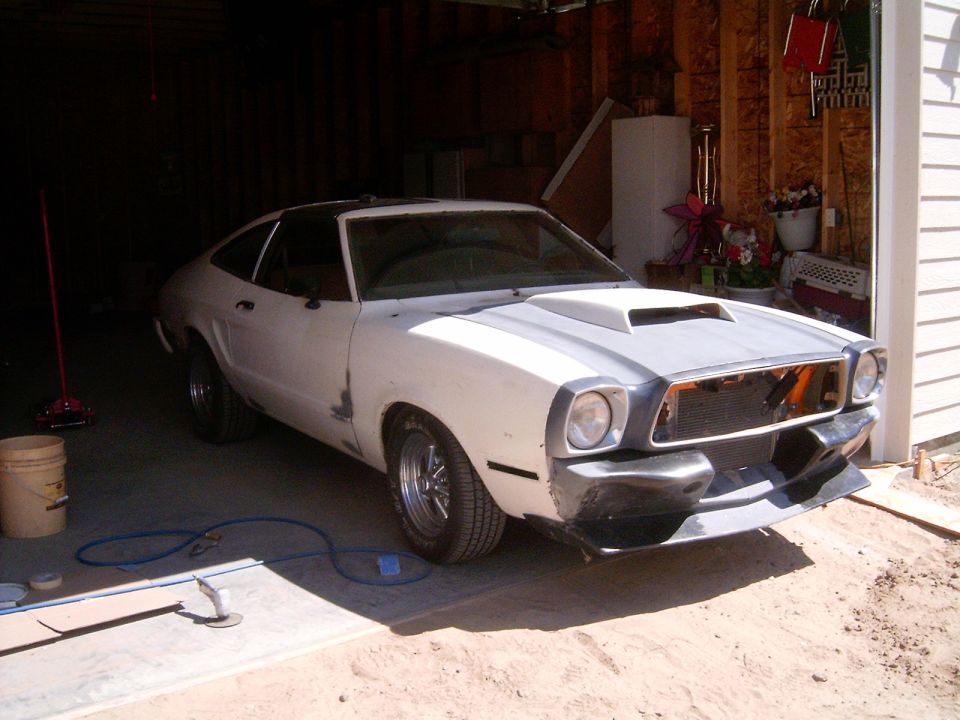 White primered Mustang II hatchback project car in open garage, front bumper and grille removed