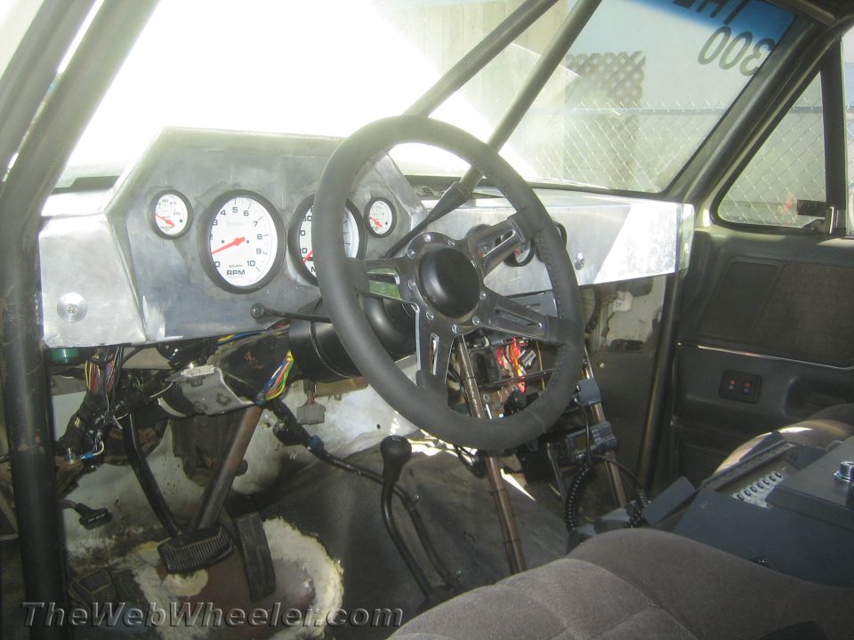 Stripped race-truck interior with roll cage, tachometer and bare steering wheel