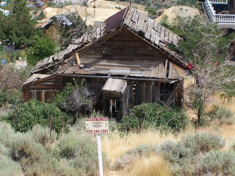 1990 Ford Bronco - A weathered, abandoned house sits on a dry, grassy hillside, with a 'Property For Sale' sign in the foreground.