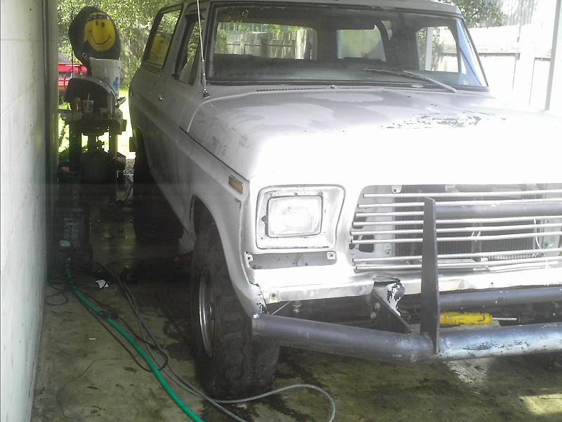 White vintage Ford truck with brush guard parked in a carport