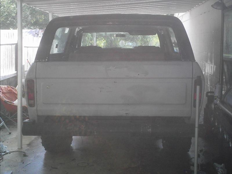 Rear of a white vintage Ford Bronco parked in a carport
