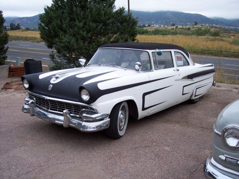 1972 Ford Ranchero - A white 1956 Ford Fairlane Crown Victoria with flame decals on the hood is parked next to another vehicle.