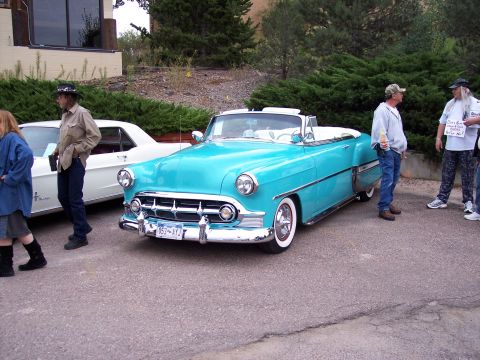 1972 Ford Ranchero - A turquoise convertible with a white top and chrome accents is parked on asphalt, with people standing nearby.