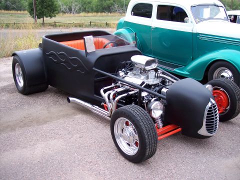 1972 Ford Ranchero - Custom hot rod with exposed engine and flame decals sits beside another vintage vehicle.