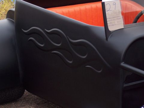 1972 Ford Ranchero - A close-up of a custom hot rod shows its matte black exterior with embossed flame graphics and bright orange upholstery.