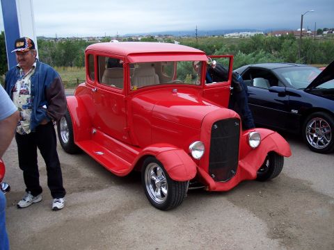 1972 Ford Ranchero - A red hot rod coupe is parked next to a dark blue car, with people standing nearby.