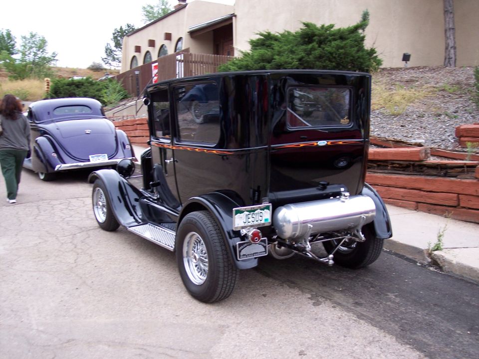 Black vintage sedan with flame pinstripes and a large silver tank, viewed from the rear