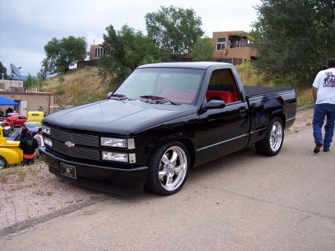 1972 Ford Ranchero - A black pickup truck with a custom grille and red interior is parked outdoors.