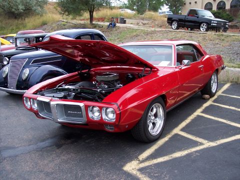 1972 Ford Ranchero - A red 1969 Pontiac Firebird is displayed with its hood open, parked beside another classic vehicle.