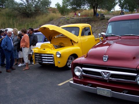 1972 Ford Ranchero - A yellow pickup truck is displayed with its hood open, alongside a red pickup truck.