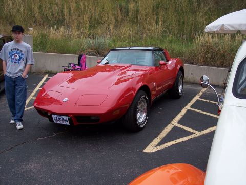 1972 Ford Ranchero - A red sports car with a black t-top is parked in a lot next to other vehicles.