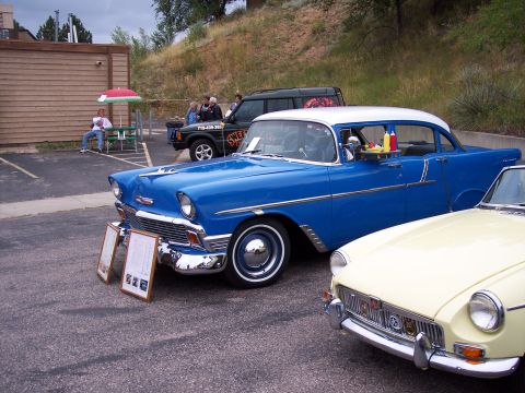 1972 Ford Ranchero - A blue and white 1955 Chevrolet sedan is parked next to a yellow MG sports car.