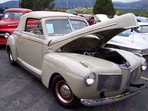 1972 Ford Ranchero - A tan 1941 convertible is displayed with its hood open, parked next to a red car.