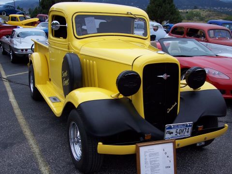 1972 Ford Ranchero - A bright yellow 1936 pickup truck is displayed with other vehicles.