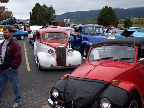 1972 Ford Ranchero - A red convertible Volkswagen Beetle and a blue pickup truck are parked at an outdoor car show with other vehicles.