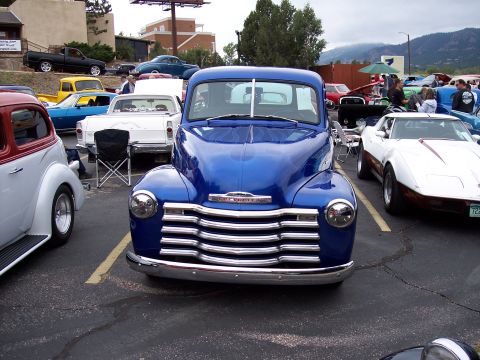 1972 Ford Ranchero - A classic blue Chevrolet pickup truck is displayed at a car show, with other vehicles visible in the background.