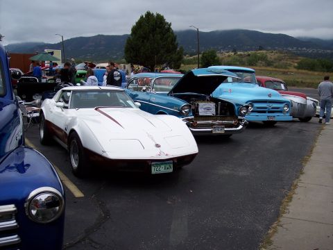1972 Ford Ranchero - A white and maroon sports car is parked in a lot with other vehicles, including a blue pickup truck and a blue sedan.