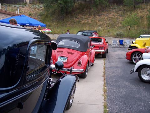 1972 Ford Ranchero - Several classic cars are parked in a lot, including a red convertible Volkswagen Beetle and a black vintage automobile.