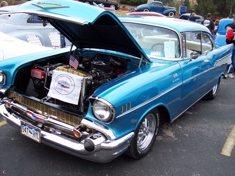 1972 Ford Ranchero - A blue 1957 Chevrolet Bel Air is displayed with its hood open, revealing the engine and a club banner.