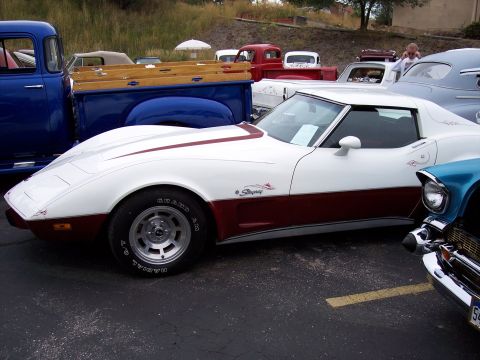 1972 Ford Ranchero - A two-tone white and maroon Chevrolet Corvette Stingray is parked next to other vehicles.
