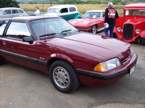 1972 Ford Ranchero - A maroon Ford Mustang GT is parked in front of other vintage vehicles at an outdoor gathering.