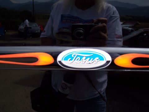 1972 Ford Ranchero - A Ford emblem with flame decals is visible on a dark surface, reflecting a person holding a camera.