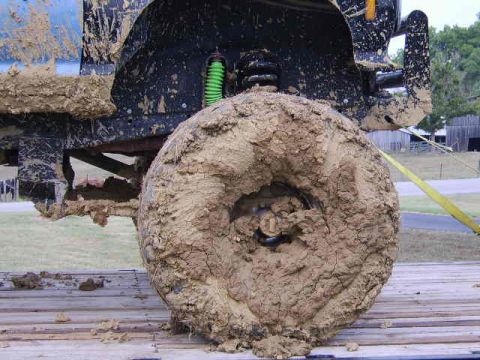 1986 Ford Ranger - Close-up of a heavily mud-caked tire and suspension system on a truck.