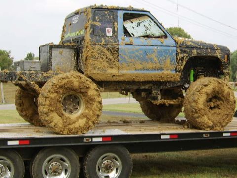 1986 Ford Ranger - This heavily modified 1986 Ford Ranger is covered in mud and features oversized tires, likely prepared for off-road activities.