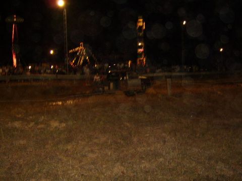 1986 Ford Ranger - A truck is visible in a muddy field at night, with carnival rides illuminated in the distance.