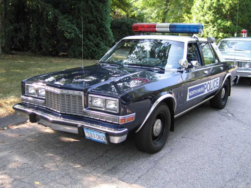 Dark blue North Haven Police sedan with red-and-blue lightbar parked under trees